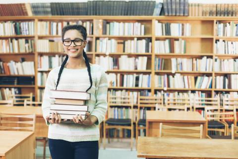 A student carrying books in a library