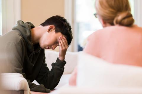 A teenager holds his head in his hands