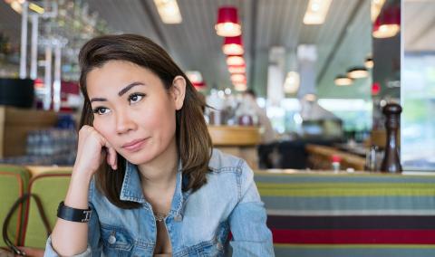 A young woman sits in a restaurant looking bored