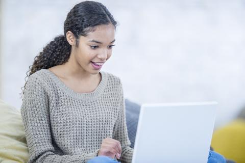 A young woman typing on a laptop