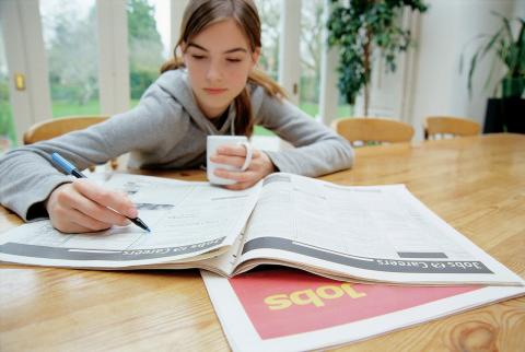 A teenage girl looks at job advertisements in a newspaper