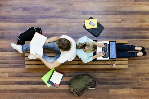 An overhead view of two students sitting back to back and studying