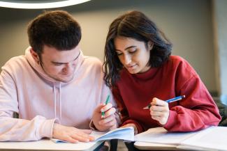 A teen girl and boy work together on some schoolwork