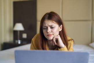 A woman using a laptop, looking confused