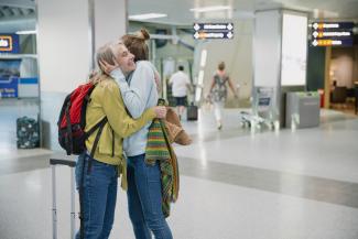 A teenage girl and an older woman hugging at an airport