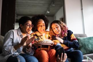 Three friends celebrate with a birthday cake