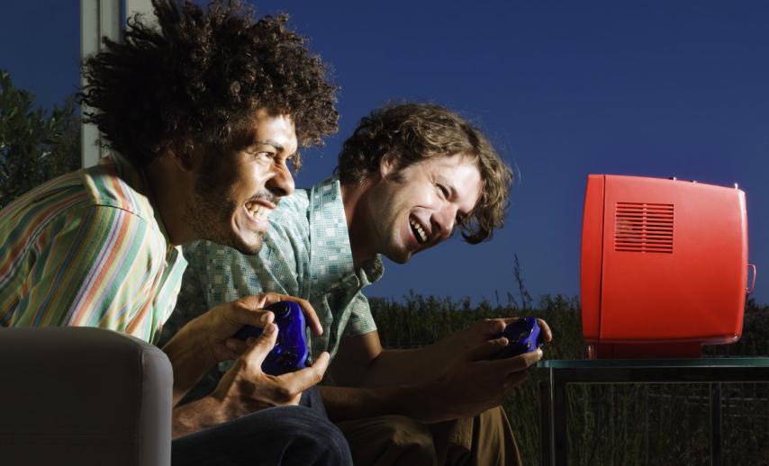 Two young men playing a video game with excited expressions
