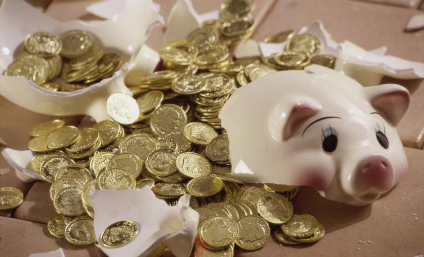 A broken piggy bank with coins spilling out