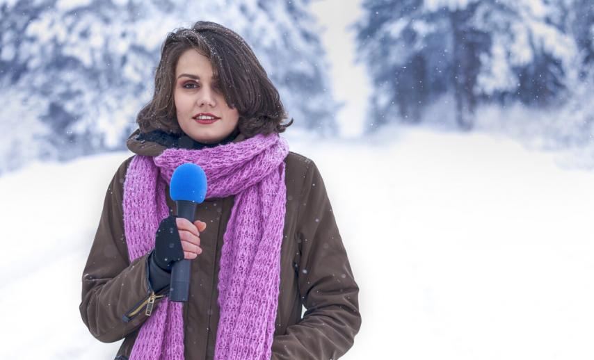 A presenter in a snowy landscape holding a microphone