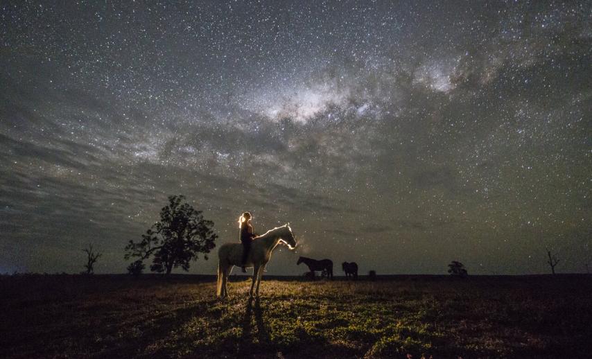 A person riding a horse under a starry sky