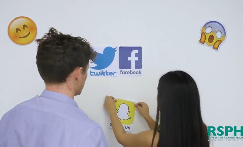 Two people looking at social media icons on a whiteboard