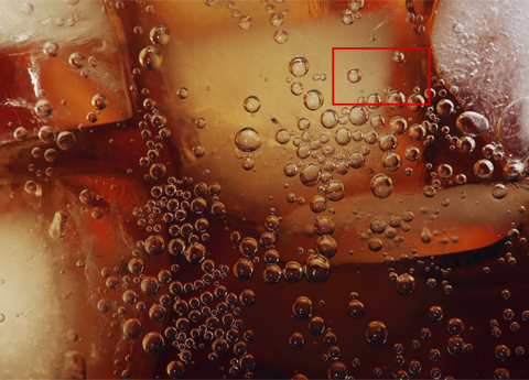 Bubbles in a glass of fizzy cola with ice